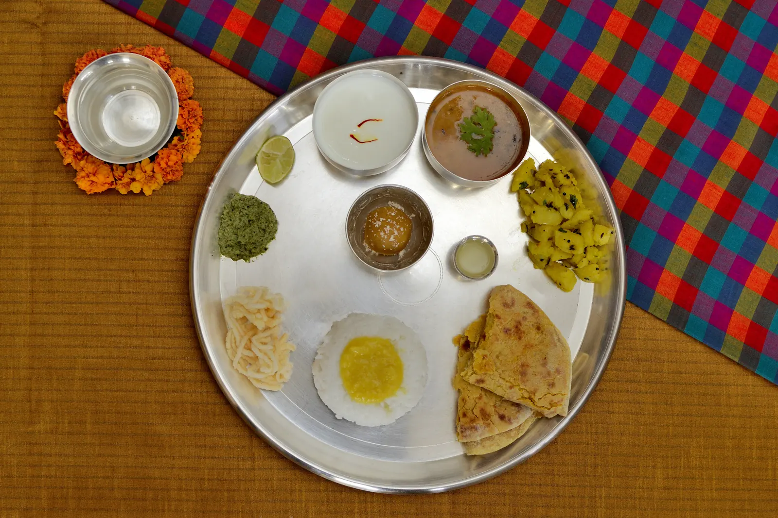 A Maharashtrian thali on a steel plate with puran poli, rice, varan, a vegetable and kheer
